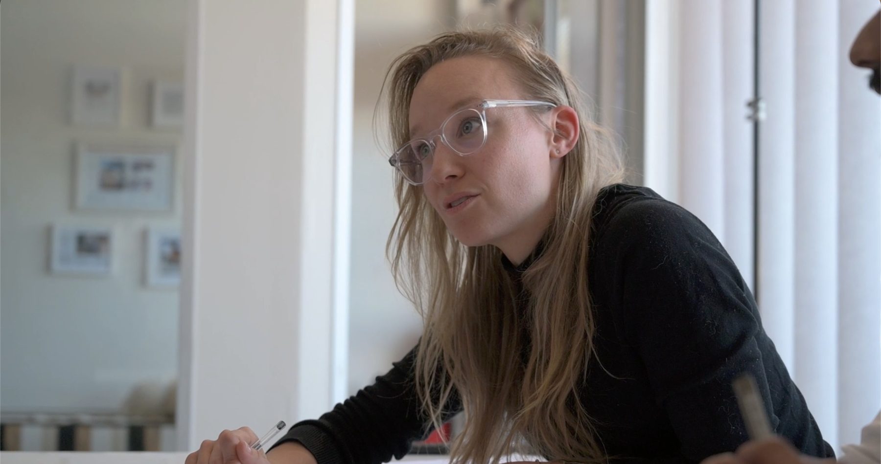 Jacqueline in glasses explaining a design across the table