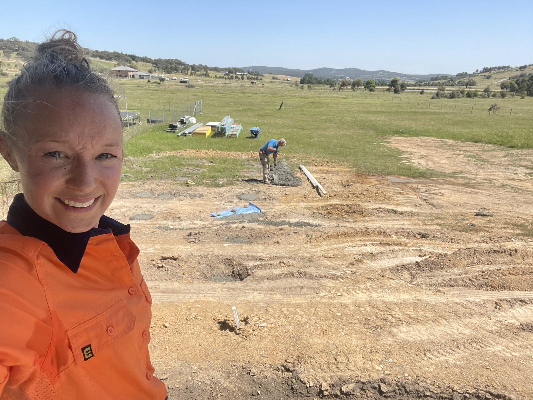 Jacqueline in a hi-vis shirt taking a selfie on a cleared construction site