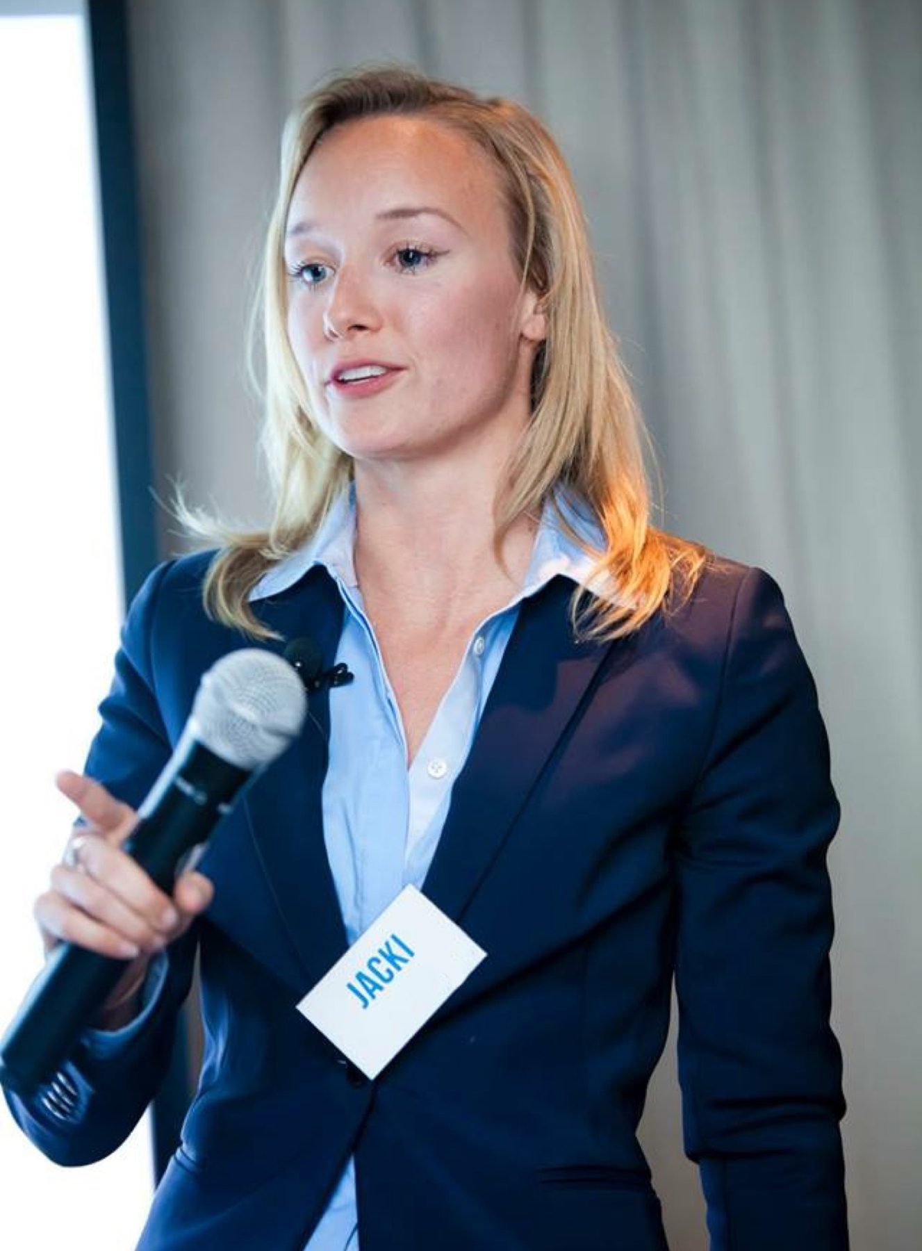 Jacqueline Valk speaking into a microphone at a business event